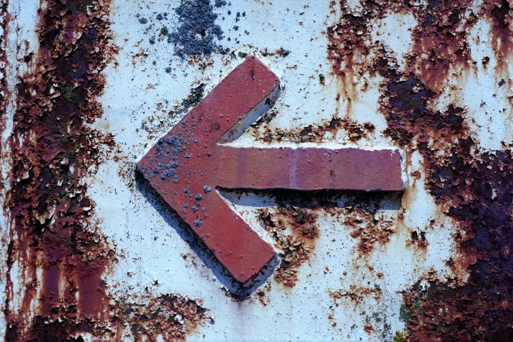 Signe de flèche rouge sur le mur de béton blanc et brun, North Vancouver, Canada, par Randy Laybourne. Trouvée sur Unsplash.com